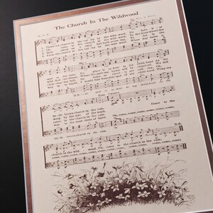May include: A vintage sheet music print of the song "The Church In The Wildwood". The sheet music is printed in brown ink on cream-coloured paper. The lyrics and musical notes are visible. The image also includes a drawing of a small brown church in a field of flowers.