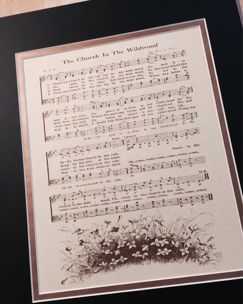 May include: A vintage sheet music print of the song "The Church In The Wildwood". The sheet music is printed in brown ink on cream-coloured paper. The lyrics and musical notes are visible. The image also includes a drawing of a small brown church in a field of flowers.