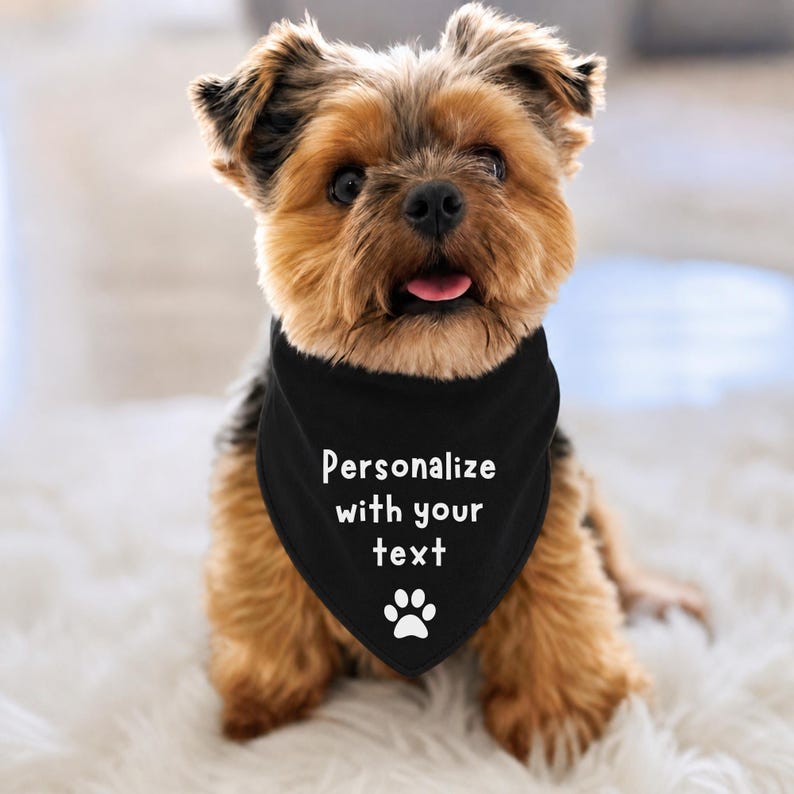 Personalize with your text dog bandana with a paw print at the bottom.  The dog is wearing a black tie on bandana with white font.