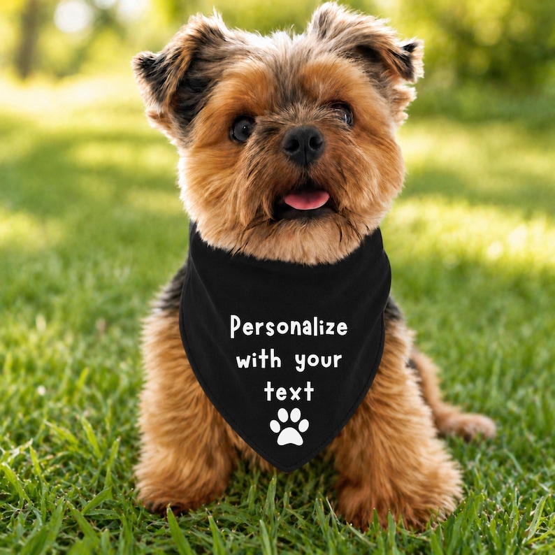 Personalize with your text dog bandana with a paw print at the bottom.  The dog is wearing a black tie on bandana with white font.