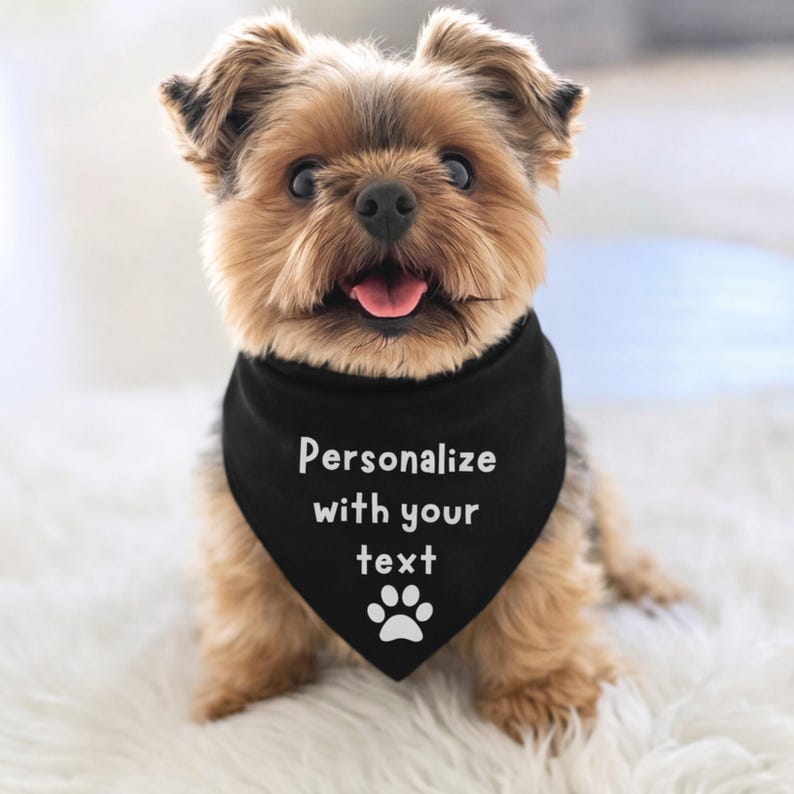 Personalize with your text dog bandana with a paw print at the bottom.  The dog is wearing a black tie on bandana with white font.