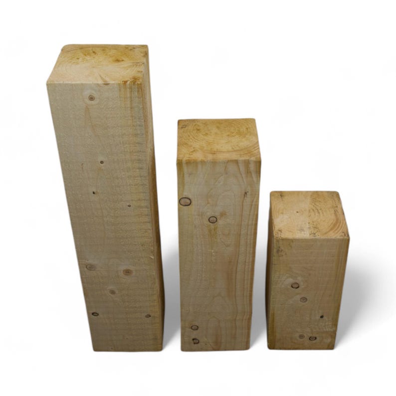 Peut inclure: Trois blocs de bois de tailles diff&eacute;rentes, empil&eacute;s par ordre d&eacute;croissant de gauche &agrave; droite. Les blocs sont en bois brun clair avec un motif de grain naturel.