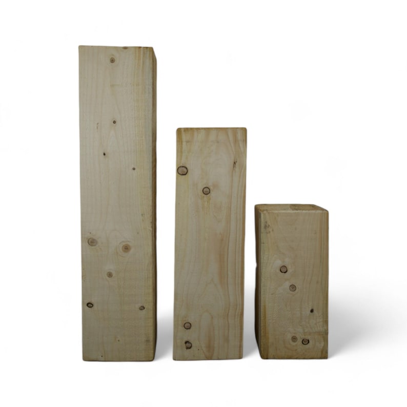 Peut inclure: Trois blocs de bois de hauteurs diff&eacute;rentes, tous en bois brun clair. Les blocs sont lisses et ont un grain de bois naturel.