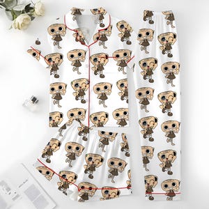 May include: A white pajama set with a repeating cartoon character pattern. The set comprises a short-sleeved button-up shirt, shorts, and long trousers. The shirt and shorts have red piping around the edges.