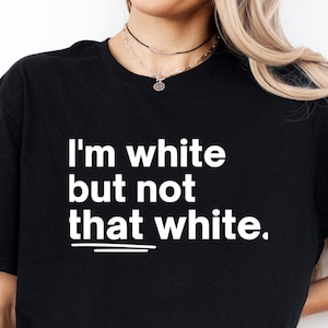 May include: Black t-shirt with the white text "I'm white but not that white." The shirt is a crew neck style and is made of a soft material. The shirt is worn by a person.