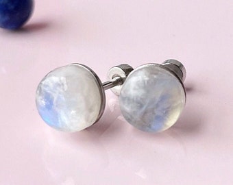 May include: A pair of silver stud earrings with round, iridescent moonstone gemstones.