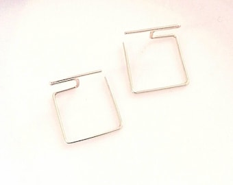 May include: A pair of silver square hoop earrings with a unique open design.