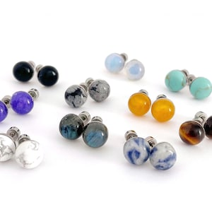 以下が含まれることがあります： アメジスト、ターコイズ、タイガーアイ、ラブラドライトなど、さまざまな半貴石を特徴とするスタッドピアスの10ペアセット。各ペアはステンレススチール製のポストで作られています。