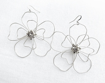 May include: A pair of silver wire earrings shaped like flowers with a cluster of silver beads in the center of each flower.