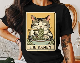 May include: Black t-shirt with a graphic of a cat eating ramen noodles. The graphic is in a vintage style with a yellow background and the text "The Ramen".
