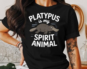 May include: Black t-shirt featuring a cartoon platypus with the text "PLATYPUS is my SPIRIT ANIMAL" in white. The platypus is depicted in shades of gray and brown, with a distinctive bill.