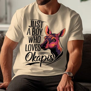 May include: A beige t-shirt with a black graphic of an okapi and the text "Just a boy who loves Okapis".