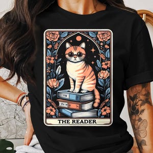 かわいい猫がタロットカードを読むアートTシャツ、花柄猫好きギフトTシャツ、ユニークなイラストシャツ、ユニセックス猫の本グラフィックトップ