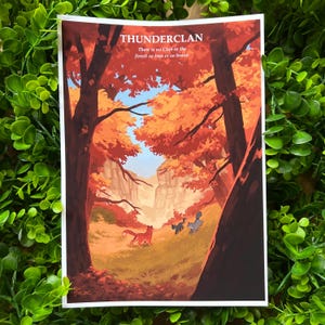 Könnte beinhalten: Ein Druck mit einer Waldszene mit orangefarbenen und roten Bäumen, einem Canyon und drei Katzen. Der Text "THUNDERCLAN" steht oben, mit dem Zitat "There is no Clan in the forest so true or so brave." unten.