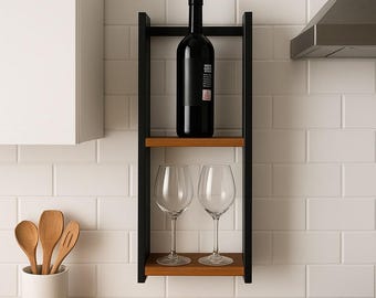 May include: A black wine bottle with a cork stopper sits on a wooden shelf. Two wine glasses are below. The shelf is part of a black metal frame. The background is a white tiled wall.