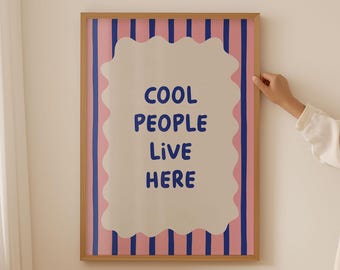May include: A framed print with pink and blue stripes and a white cloud-shaped speech bubble that says "COOL PEOPLE LIVE HERE".