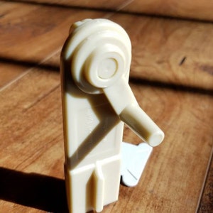 May include: A white plastic crank handle with a round knob and a small handle. The crank is designed to be used with a window blind or shade.