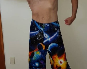 May include: Wide-leg pants with a vibrant space-themed design featuring planets, galaxies, and nebulae in shades of blue, purple, and orange. The pants are made of a soft, flowing fabric.