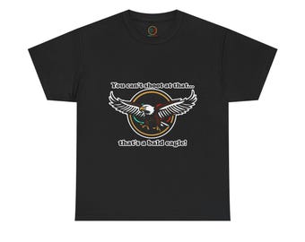 May include: Black t-shirt featuring a graphic of a bald eagle with outstretched wings, encircled by a gold ring. The text reads, "You can't shoot at that... that's a bald eagle!"