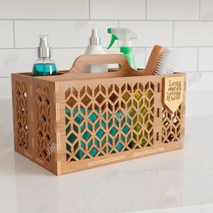 May include: A wooden organiser with a handle, holding cleaning supplies. The organiser has a geometric design and contains bottles, a brush, and a spray bottle. A small wooden tag reads "Less mess, less stress."