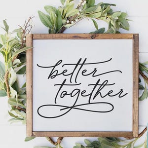May include: A wooden framed sign with the words "better together" in elegant black script. The sign is surrounded by greenery and is suitable for home decor. The image also includes digital download cut file graphics.