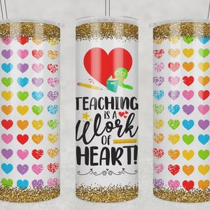 May include: A white tumbler with a gold glitter top and bottom. The tumbler features a design of colorful hearts and the text "Teaching is a Work of Heart!" with a red heart and a green worm reading a book.