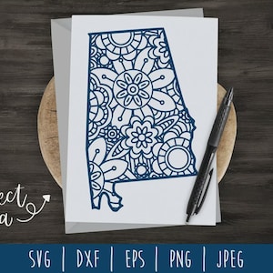 May include: A white card with a floral design in the shape of Alabama, with a pen. The card is on a wooden surface. The words "project idea" are written in cursive. The card is surrounded by a grey envelope.