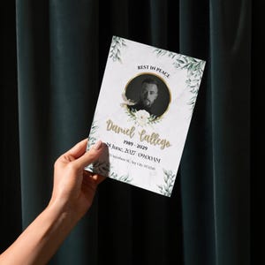 Può includere: Un cartoncino per programma funebre con sfondo in marmo bianco e dettagli a foglie verdi. Mostra un ritratto circolare in bianco e nero di un uomo, il testo REST IN PEACE, Daniel Gallego, 1989-2029, 28 June, 2027 09:00AM e 123 Anywhere St., Any City, ST 12345.