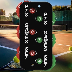 May include: A black tennis scorekeeper with red and green accents. The scorekeeper displays the points, games, and set scores. The background shows a tennis court with a tennis ball and racket.