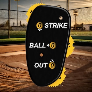 May include: Black baseball scorekeeper with yellow dials. The dials show 0 strikes, 1 ball, and 0 outs.