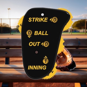 May include: Black baseball scorekeeper with yellow dials. The dials show "Strike 0", "Ball 0", "Out 0", and "Inning 1".