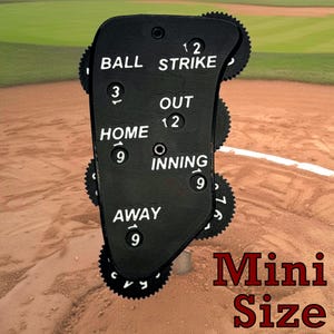 May include: Black baseball scorekeeper with rotating dials for balls, strikes, outs, innings, home and away teams. The dials are numbered 1-9 and 12. The text "Mini Size" is printed in red below the scorekeeper.