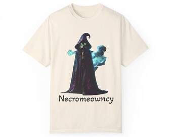 May include: A beige t-shirt with a black cat wearing a purple robe and a pointed hat. The cat has green eyes and is surrounded by a blue and purple mist. The text "Necromeowncy" is printed below the image.