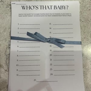 May include: A white printable game sheet with the title "Who's That Baby?" and instructions to match the guest to the baby photo. The sheet has 25 numbered lines for writing names.