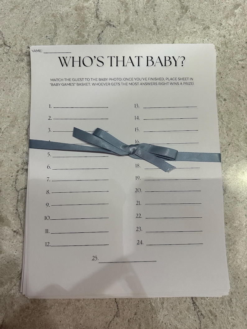 May include: A white printable game sheet with the title "Who's That Baby?" and instructions to match the guest to the baby photo. The sheet has 25 numbered lines for writing names.
