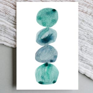 Modern abstract artwork of stacked pebbles in shades of blue and green. Original hand-drawn artwork using watercolour. Wall art for home