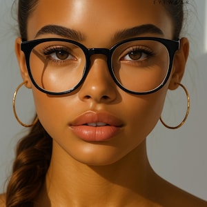 May include: A close-up of a person wearing black round-framed eyeglasses with a white inner rim. The person is also wearing gold hoop earrings. The brand name "ERATIQUE EYEWEAR" is displayed at the top.