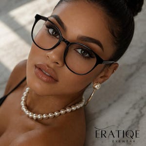 May include: A woman wearing black-framed eyeglasses, a pearl necklace, and gold hoop earrings with pearl drops. The image includes the text "ERATIQE EYEWEAR". The woman has her hair up in a bun.