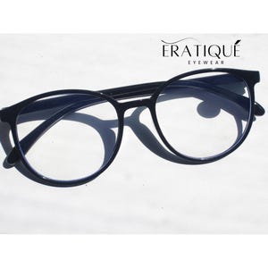 May include: Black round-frame eyeglasses with clear lenses. The glasses have a sleek, modern design. The brand name "ERATIQUE EYEWEAR" is displayed above the glasses.