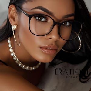 May include: A woman wearing black-framed eyeglasses with a round shape. She is also wearing gold hoop earrings and a pearl necklace. The brand name "ERATIQ EYEWEAR" is visible in the image.