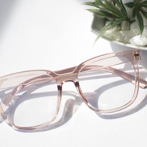 May include: A pair of pink square-shaped eyeglasses with clear lenses.