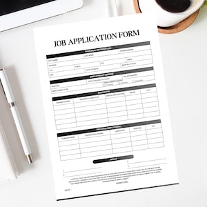 May include: A white job application form with the title "JOB APPLICATION FORM" in bold black letters. The form includes sections for personal information, employment desired, education, and previous employment. A white pen and notepad are visible.