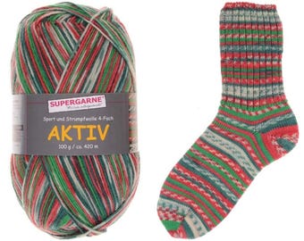May include: A ball of Aktiv yarn and a knitted sock. The yarn is a mix of red, green, and white. The sock has a similar color pattern. The yarn label reads "SUPERGARNE AKTIV 100 g / ca. 420 m".