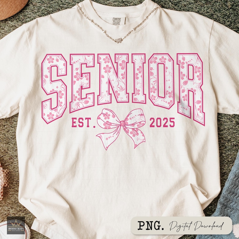Pu&ograve; includere: T-shirt color crema con la scritta "SENIOR" in grandi lettere rosa a fantasia floreale. Sotto la scritta, "EST. 2025" e un fiocco rosa. La maglietta &egrave; un download digitale, formato PNG.