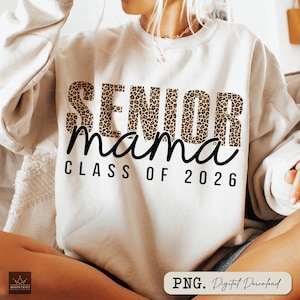 Può includere: Una felpa color crema con le parole "SENIOR mama CLASS OF 2026" stampate sul davanti. La parola "SENIOR" è in un motivo leopardato. Il testo è in corsivo nero. La felpa ha maniche lunghe.
