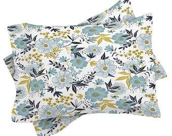 May include: Two white pillowcases with a floral pattern. The design features large blue flowers with yellow centers, smaller yellow flowers, and dark blue leaves and stems. The pillowcases are a decorative bedding item.