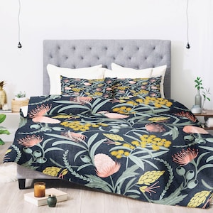 May include: A navy blue duvet cover with a floral pattern featuring pink, yellow, and green flowers. The duvet cover is on a bed with two matching pillowcases.