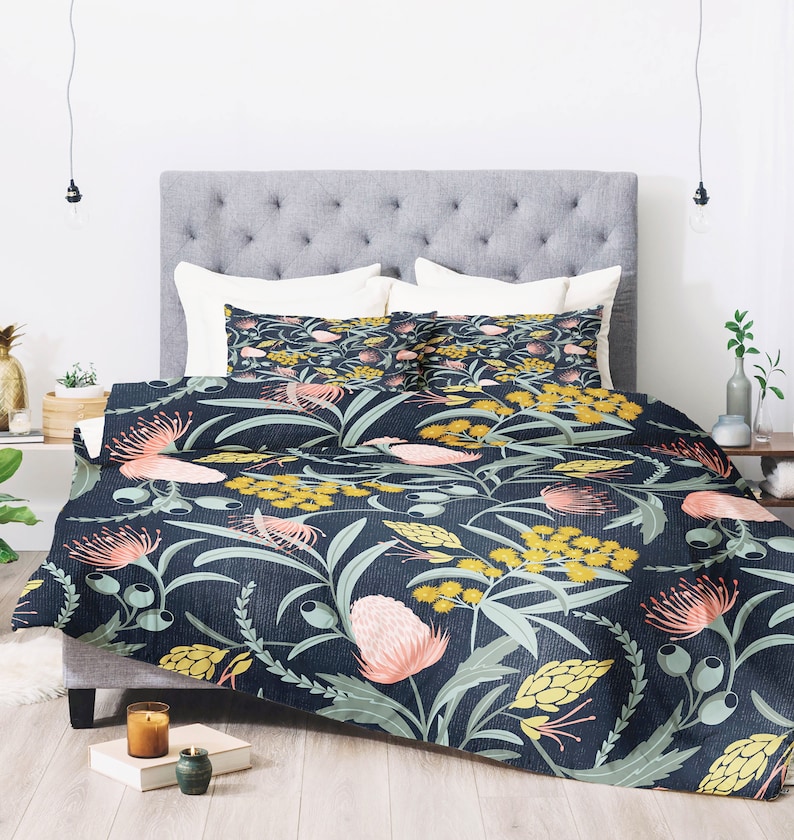 May include: A navy blue duvet cover with a floral pattern featuring pink, yellow, and green flowers. The duvet cover is on a bed with two matching pillowcases.
