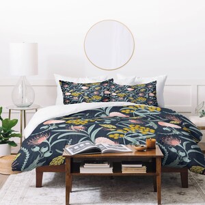 May include: A navy blue duvet cover with a floral pattern featuring pink, yellow, and green flowers. The duvet cover is on a bed with two matching pillowcases.