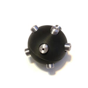 May include: A black rubber ball with six silver metal spikes. The ball is about the size of a golf ball.